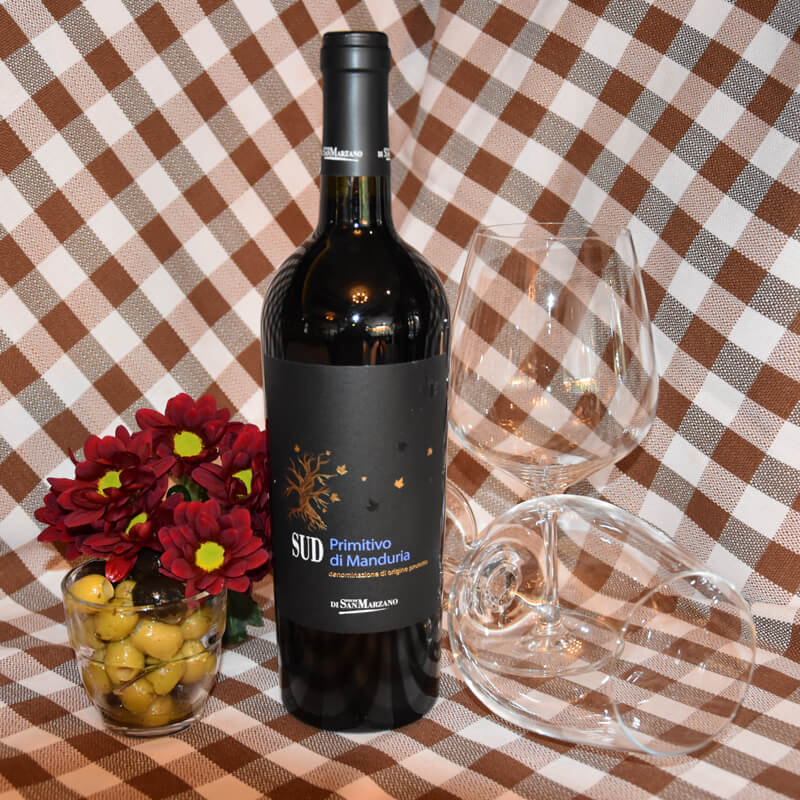 Die Weinsorte Feudi di San Marzano - Primitivo di Manduria SUD mit zwei Gläsern auf einem Tisch