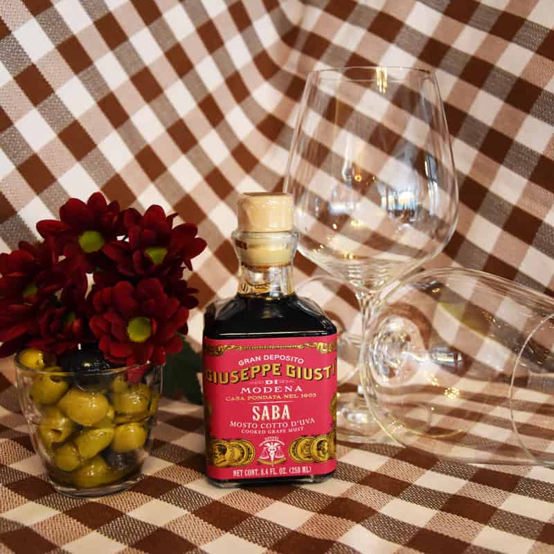 Die Mustsorte Saba – Cooked Grape Must mit zwei Gläsern auf einem Tisch